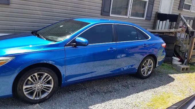 Blue Toyota Camry with a fresh shine, parked on gravel